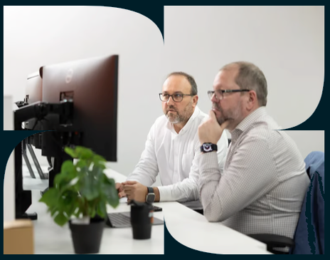 Two colleagues reviewing a dashboard together on a desktop monitor